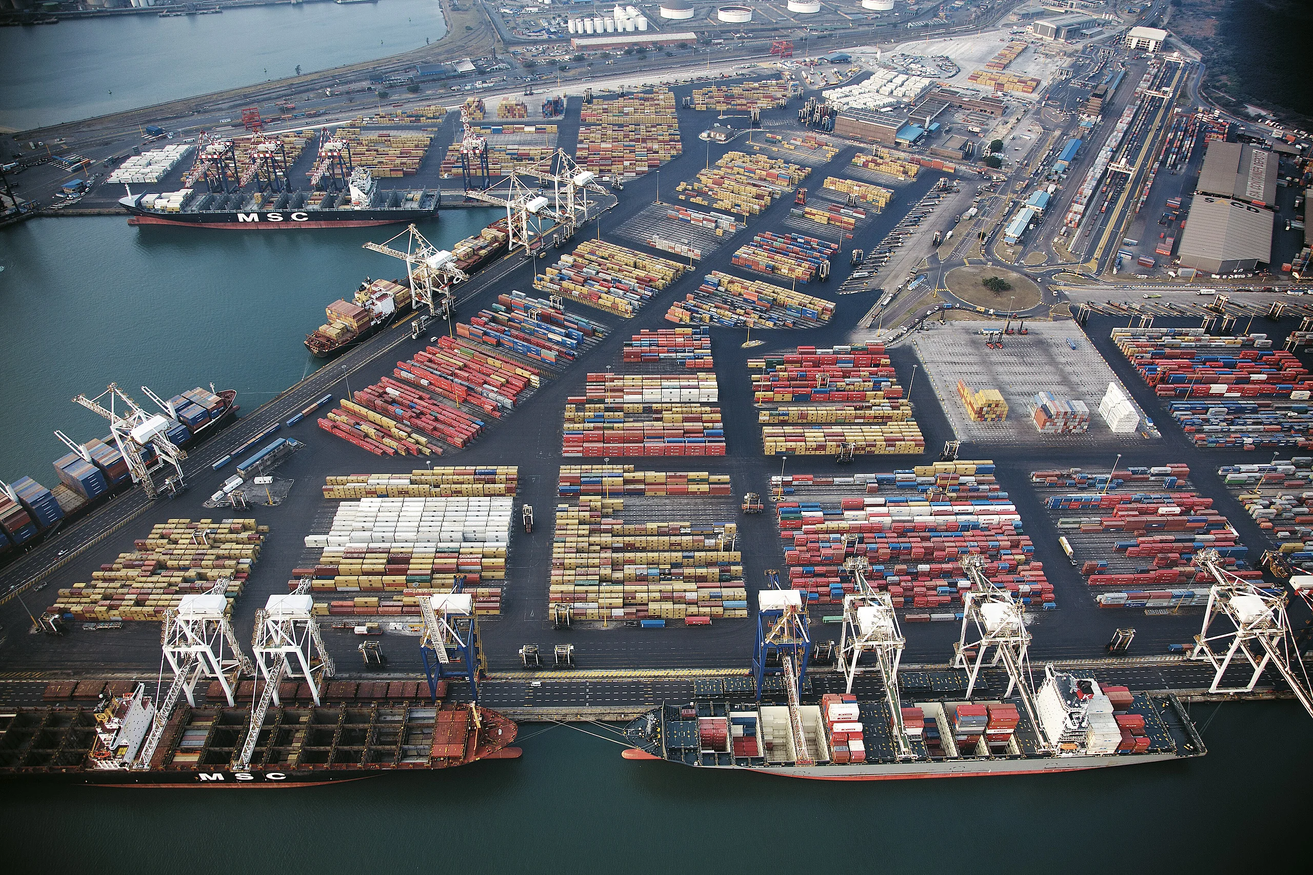Aerial view of a container port with cranes and stacked shipping containers